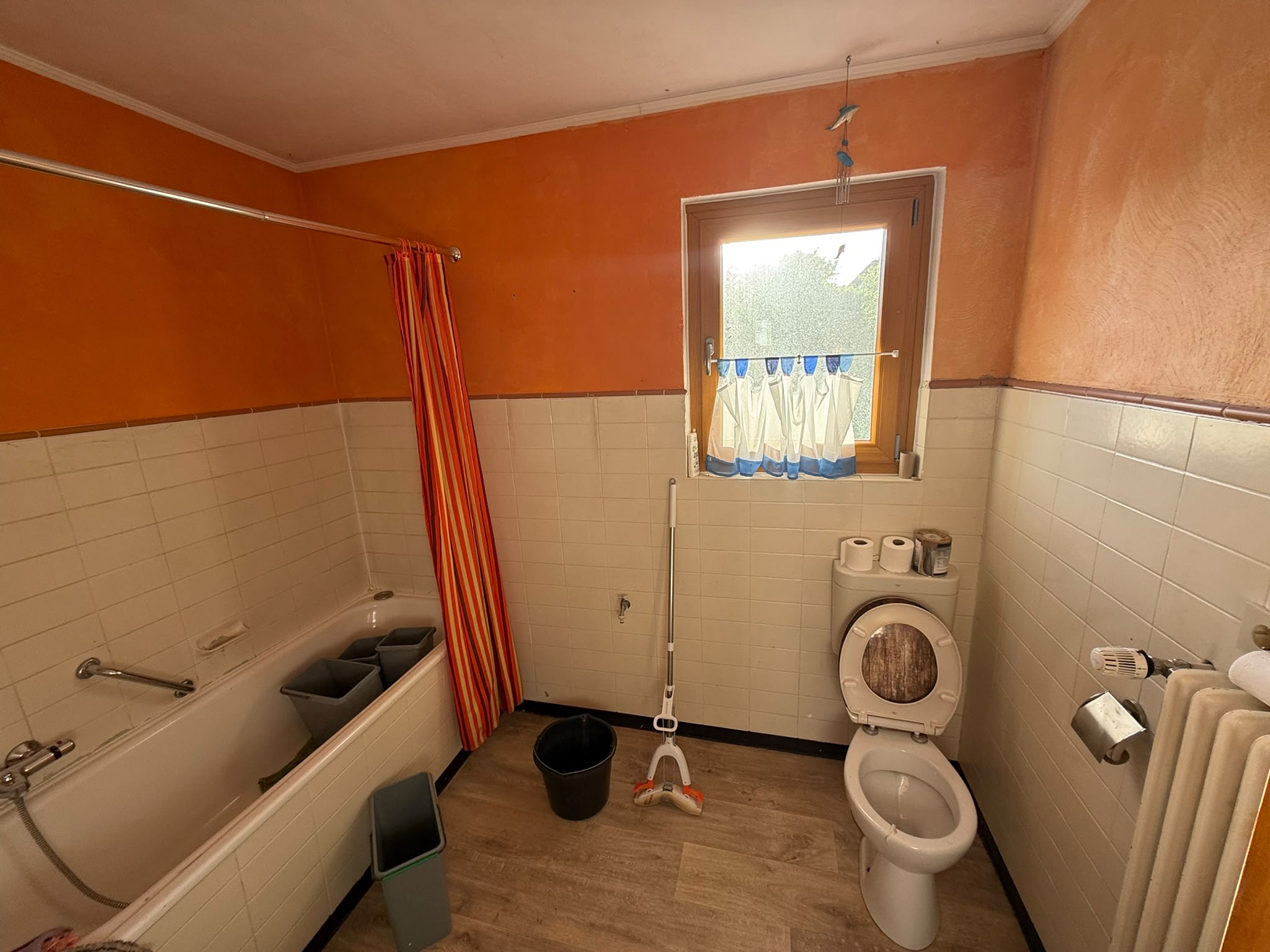 Badsanierung Lübbecke: Badezimmer vor der Sanierung mit Badewanne, WC und älteren Wandfliesen