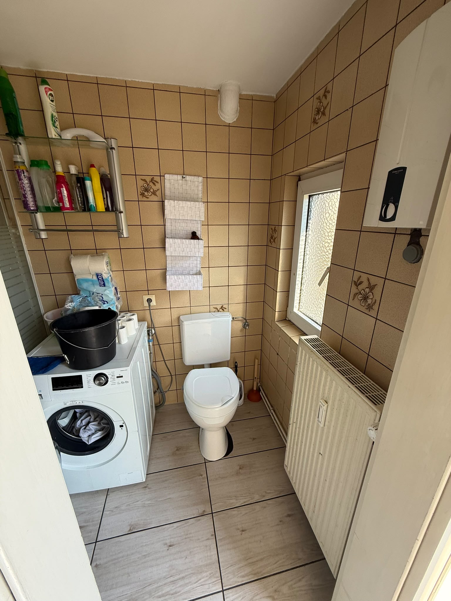 Badsanierung Lübbecke: Badezimmer vor der Sanierung mit WC, Waschmaschine und älteren Wandfliesen
